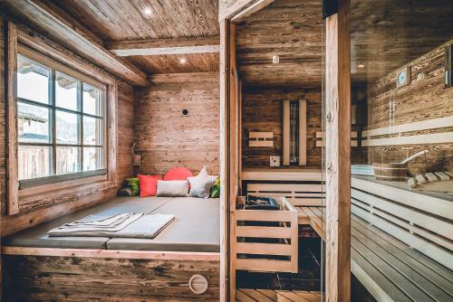 a room with a bed in a wooden cabin at Relais & Châteaux Gut Steinbach Hotel Chalets SPA in Reit im Winkl