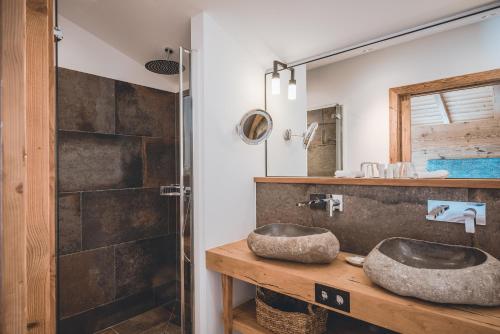 a bathroom with a stone sink and a shower at Relais & Châteaux Gut Steinbach Hotel Chalets SPA in Reit im Winkl