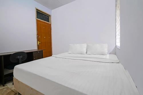 een wit bed in een kamer met een bureau bij OYO Life 92835 Maya Adipuri in Bandung
