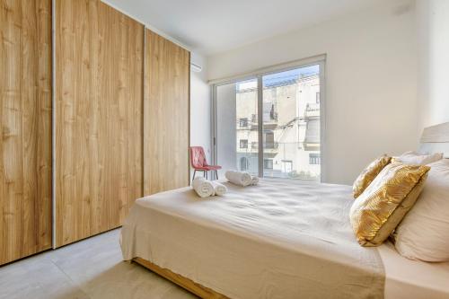 een slaapkamer met een bed met een stoel en een raam bij Annitchka Mansions - Apartment in central Malta in Birkirkara