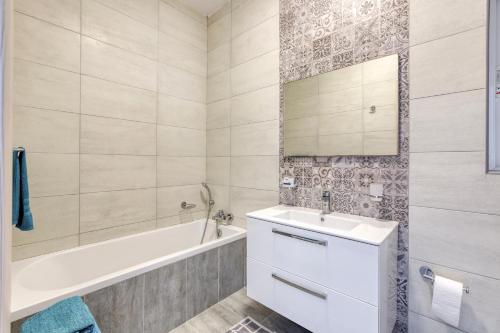 een witte badkamer met een bad, een wastafel en een bad tubermott bij Annitchka Mansions - Apartment in central Malta in Birkirkara