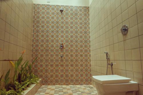a bathroom with a toilet and a tiled shower at White Serenity Villa Udupi in Udupi