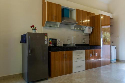 a kitchen with a black refrigerator and wooden cabinets at White Serenity Villa Udupi in Udupi