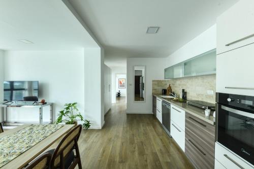 a kitchen with white cabinets and a wooden floor at Modern & Bright 3BR Apt by Sea N' Rent in Tel Aviv