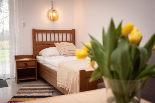 um quarto com uma cama e um vaso com flores amarelas em Zubrzyckie Pokoje em Zubrzyca Dolna
