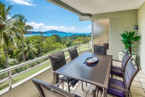 a table and chairs on a balcony with a view of the ocean at POINCIANA 101 HAMILTON ISLAND CENTRALLY LOCATED 3 BEDROOM, plus BUGGY!! in Hamilton Island