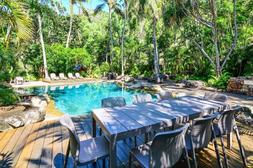 a table and chairs in front of a swimming pool at POINCIANA 101 HAMILTON ISLAND CENTRALLY LOCATED 3 BEDROOM, plus BUGGY!! in Hamilton Island
