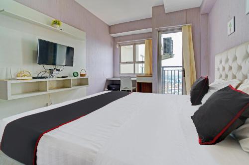 ein Schlafzimmer mit einem großen weißen Bett und einem TV in der Unterkunft OYO Life 92548 M-square Apartment By Lins Pro in Bandung