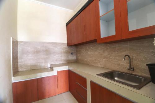 a kitchen with wooden cabinets and a sink at OYO Life 92707 D-akomiba Residence in Jambi