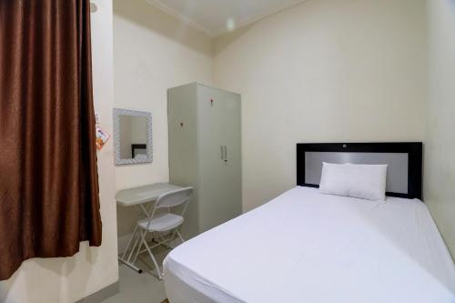 a bedroom with a large white bed and a chair at OYO Life 92707 D-akomiba Residence in Jambi