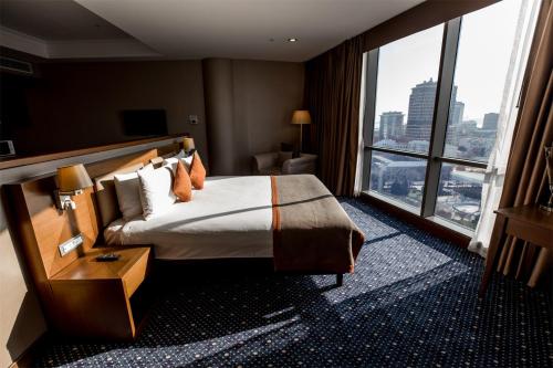 pokój hotelowy z łóżkiem i dużym oknem w obiekcie Parkside Hotel & Apartments w mieście Baku