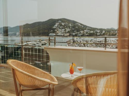 a balcony with two chairs and a table with a wine glass at Aguas de Ibiza Grand Luxe Hotel - Small Luxury Hotel of the World in Santa Eularia des Riu