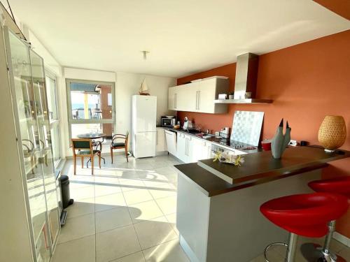 - une cuisine avec un comptoir et des chaises rouges dans l'établissement La Perle des Dunes - Vue imprenable Mer & Dunes, à Leffrinckoucke