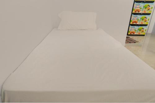 uma cama branca num quarto com um frigorífico em OYO Life 92918 Rumah Kost Arrahma Syariah em Nganjuk