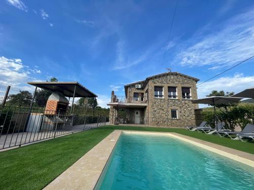 une maison avec une piscine en face d'un bâtiment dans l'établissement Ca la Joia Casa con piscina privada en la Vall d'en Bas, à Les Preses