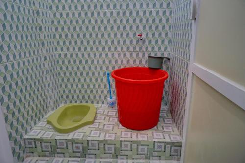 um balde vermelho no canto de uma casa de banho em OYO Life 92918 Rumah Kost Arrahma Syariah em Nganjuk