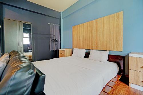ein Schlafzimmer mit einem weißen Bett und einem Ledersofa in der Unterkunft OYO Life 92984 The Suites Metro Apartement By Echie Property in Bandung