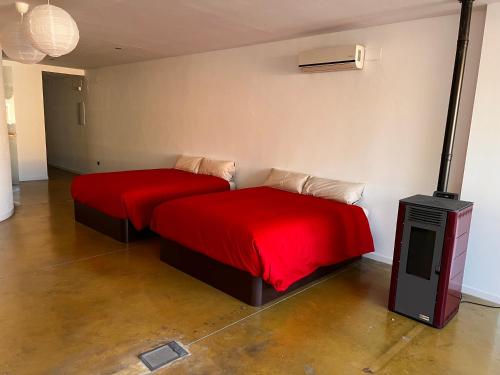 two beds in a room with red sheets and a heater at Muy Céntrico y Amplio in Alcázar de San Juan