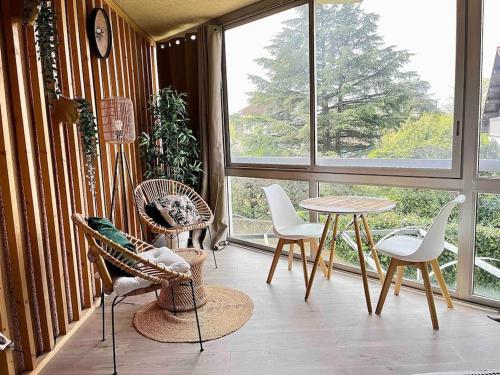 Habitación con sillas, mesa y ventanas. en The Jungle Studio, loggia & parking dans résidence, en Romans-sur-Isère