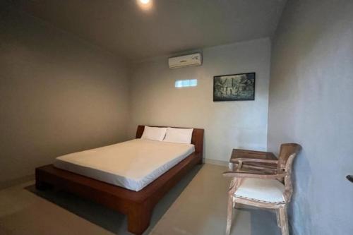 um pequeno quarto com uma cama e uma cadeira em OYO 93072 Asri Homestay Syariah em Parit