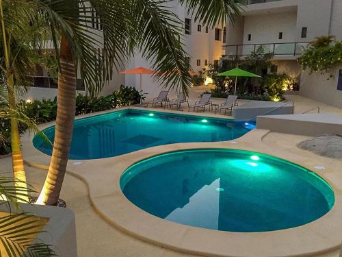 a swimming pool with a palm tree and a building at 2095 - Cosmo 8A1 in Tangolunda