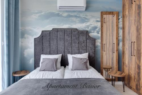 - une chambre avec un grand lit et une tête de lit grise dans l'établissement Apartament Basior, Laguna Beskidów, à Zarzecze