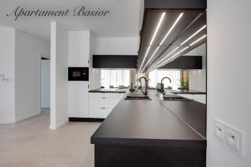 une cuisine avec des armoires blanches et des comptoirs noirs dans l'établissement Apartament Basior, Laguna Beskidów, à Zarzecze