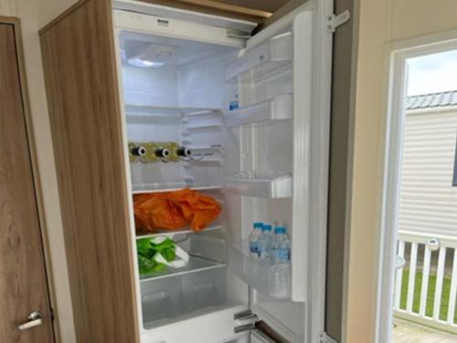 a refrigerator with its door open with food and water bottles at 3 Bed 2 Bath Static Mobile Home On Fantastic Park in Mablethorpe