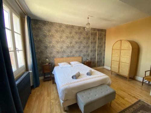 um quarto com uma cama branca e uma grande janela em La maison familiale em Auxerre