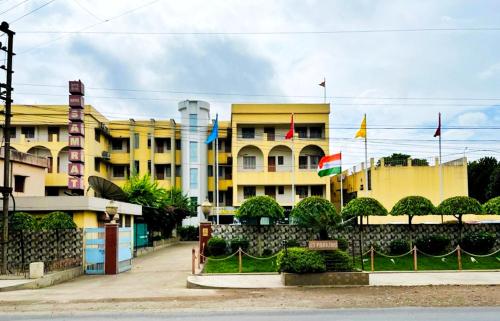 a yellow building with flags in front of it at Hotel Samrat in Baharampur