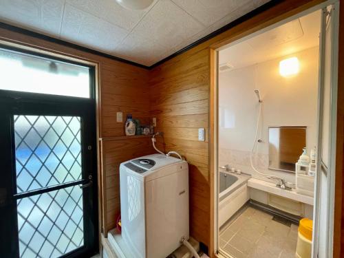 a bathroom with a small refrigerator and a bath tub at Yakushima Umigame house　屋久島 海がめの里 蘭亭 in Yakushima