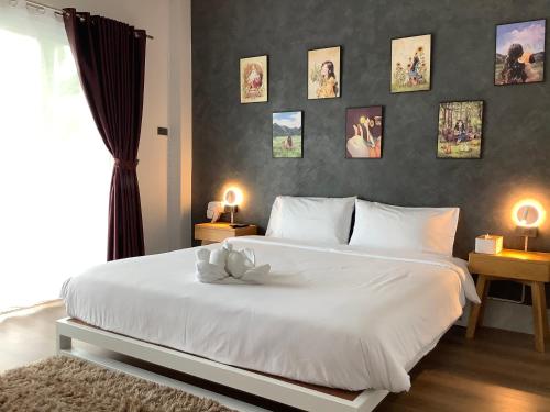 een slaapkamer met een wit bed met foto's aan de muur bij ฝันดี Fandicottage in Betong