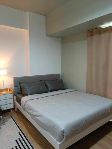 1 dormitorio con 1 cama blanca y ventana en Abreeza place T-2, en Davao City