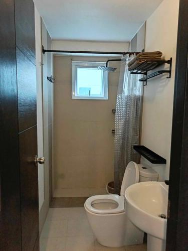a bathroom with a toilet and a sink and a window at Abreeza place T-2 in Davao City