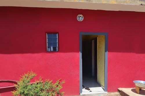 a red building with a red wall and a door at Maison 2 chambres avec jardin. in Mamoudzou