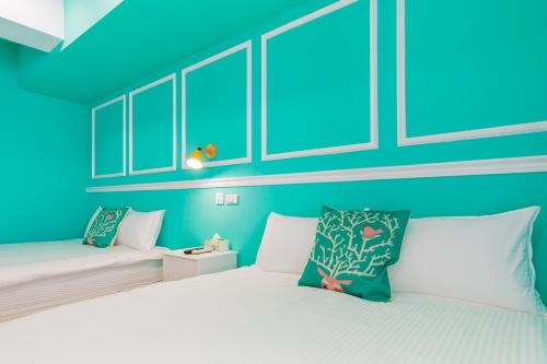 two beds in a room with blue walls at Kaohsiung I Hi Hotel in Kaohsiung