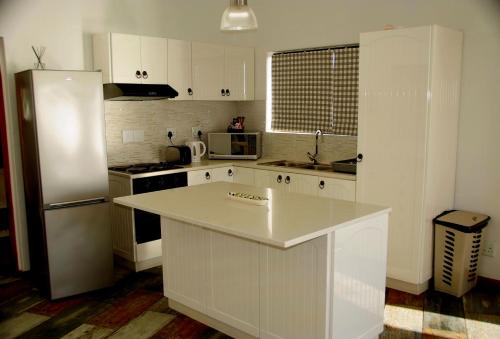 a kitchen with white cabinets and a white refrigerator at The Cormorant House in Lüderitz