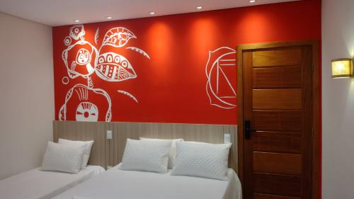a bedroom with two beds and a red wall at Pousada Boutique Raio de Luz in Ouro Preto