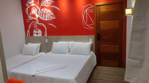 a bedroom with two beds and a red wall at Pousada Boutique Raio de Luz in Ouro Preto