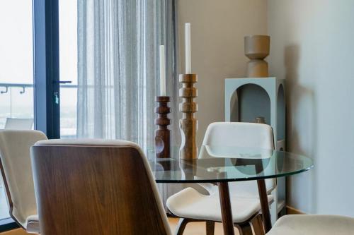 a dining room with a glass table and white chairs at AYA Boutique - Cozy 1BR Apartment with Panoramic City Views in Dubai