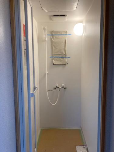 La salle de bains est pourvue d'une douche et d'une serviette. dans l'établissement Nostime lodge 女性限定 female only, à Kitakyūshū