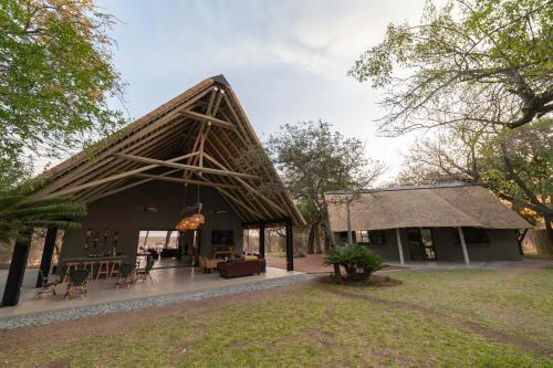 ein Haus mit einem Strohdach und einem Hof in der Unterkunft Tomo Safari Lodge in Hoedspruit