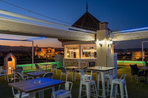 a rooftop patio with tables and chairs at night at Hesperia Córdoba in Córdoba