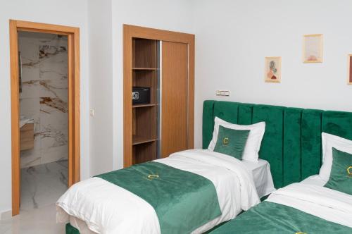 a bedroom with two beds and a green headboard at Hotel Golden Sunset Dakhla in Dakhla