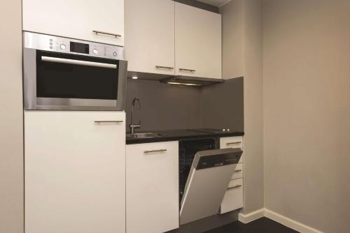 a kitchen with white cabinets and a microwave at Adina Apartment Hotel Hamburg Michel in Hamburg