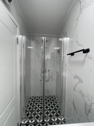 d'une douche avec une porte en verre et un sol noir et blanc. dans l'établissement הטרקלין של לינוי - 5 דקות נסיעה מהים, à Ashkelon