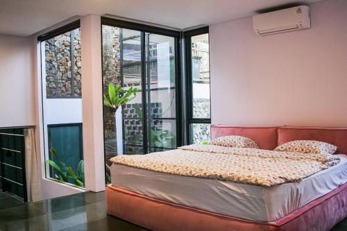 a bedroom with a bed and a large window at MALLO VILLA - DAGO VILLAGE - NEW VILLA & FURNISH in Bandung