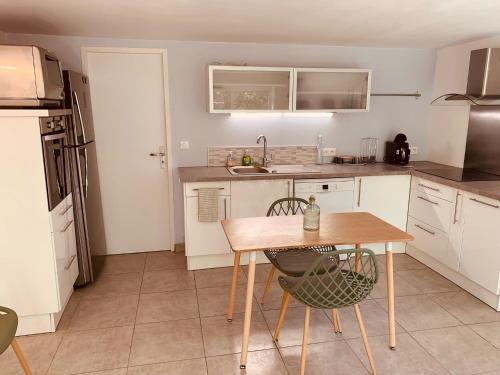 cocina con armarios blancos y mesa de madera en Appartement indépendant avec jardin et accès piscine, en Nimes