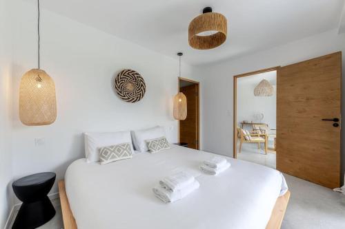 ein weißes Schlafzimmer mit einem weißen Bett und einem Stuhl in der Unterkunft VILLA KASBAR avec spa privé 4 étoiles in Tizac-de-Curton