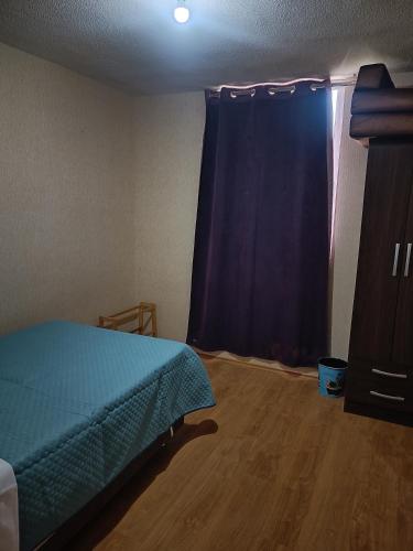 1 dormitorio con cama y cortina azul en Apartamento en chiclayo Perú, en Chiclayo